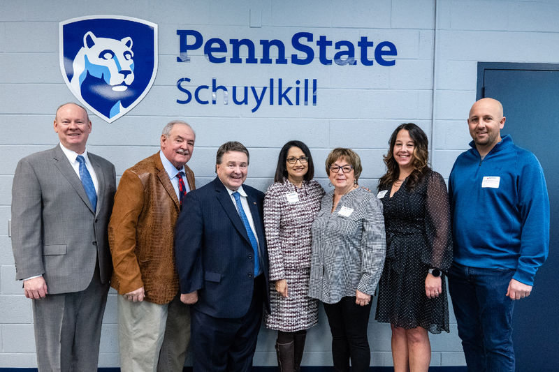 Attendees from the Schuylkill Chamber Business Executive Forum pose in front of a Penn State logo