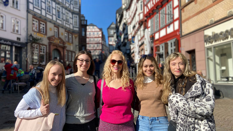 A group of students and instructors pose on cobblestone street in historical German town.