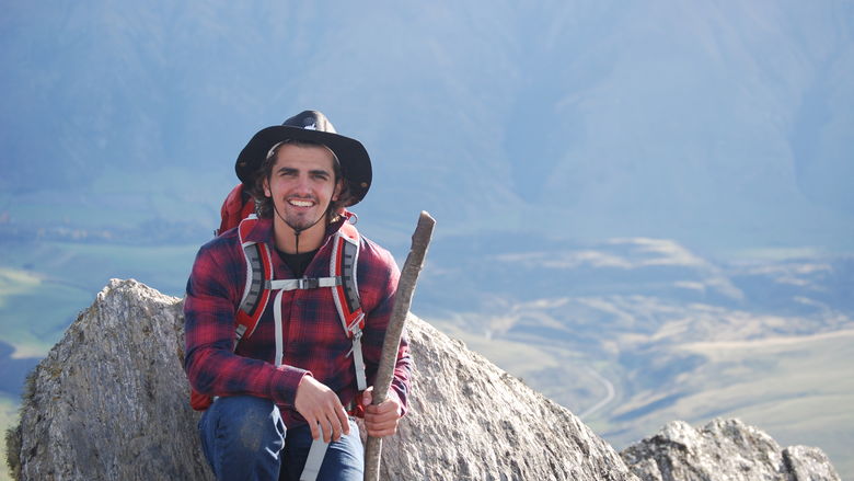 Nico Granito sits atop a mountain in New Zealand