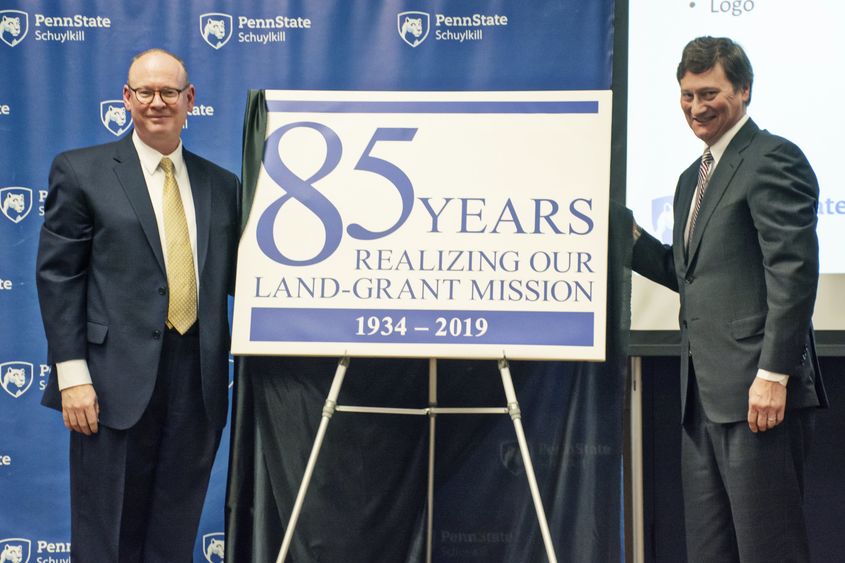 Chancellor Patrick Jones and Schuylkill advisory board member Richard Wiest unveil the 85th anniversary logo
