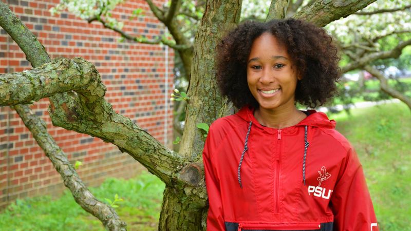 De'Airra Drayton Tilley poses next to a flowering tree on Schuylkill campus