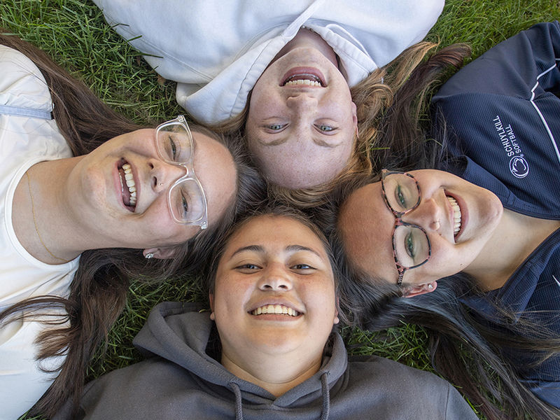 Four girls laying with heads together in grass