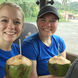 Two students sit in a chartered bus drinking from coconuts with straws coming out of the top