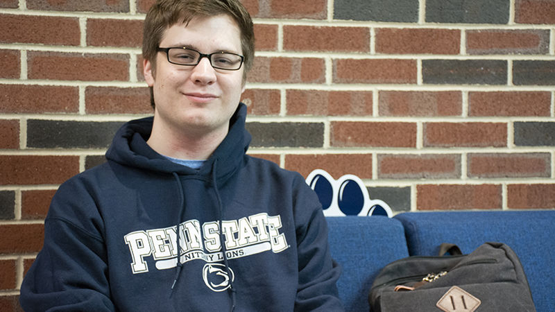 Brady Seigfried sits on a plush blue couch in the Student Community Center