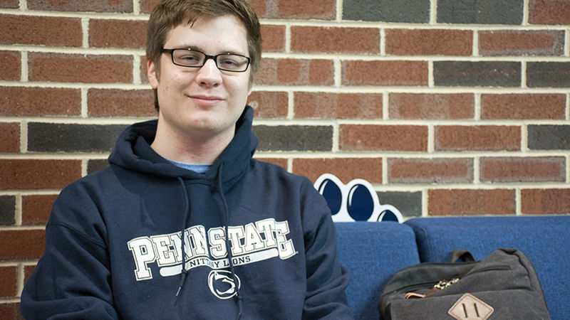 Brady Seigfried sits on a plush blue couch in the Student Community Center
