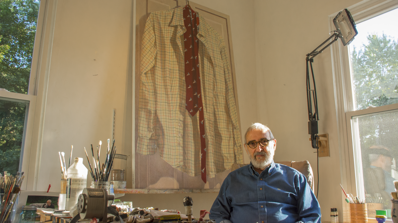 Bob Stickloon sits next to a painting in his home studio.
