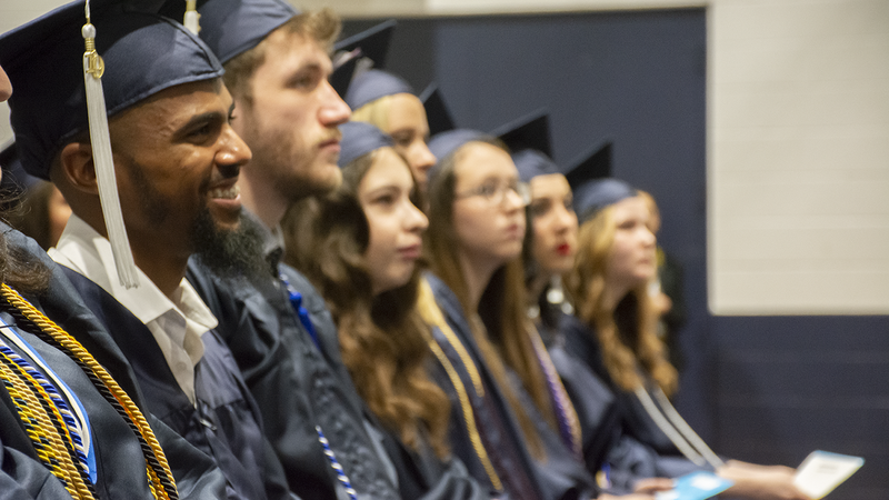 Administration of Justice students grin while Chancellor Patrick Jones confers their degrees in Penn State Schuylkill's gymnasium at the campus' 74th commencement ceremony.