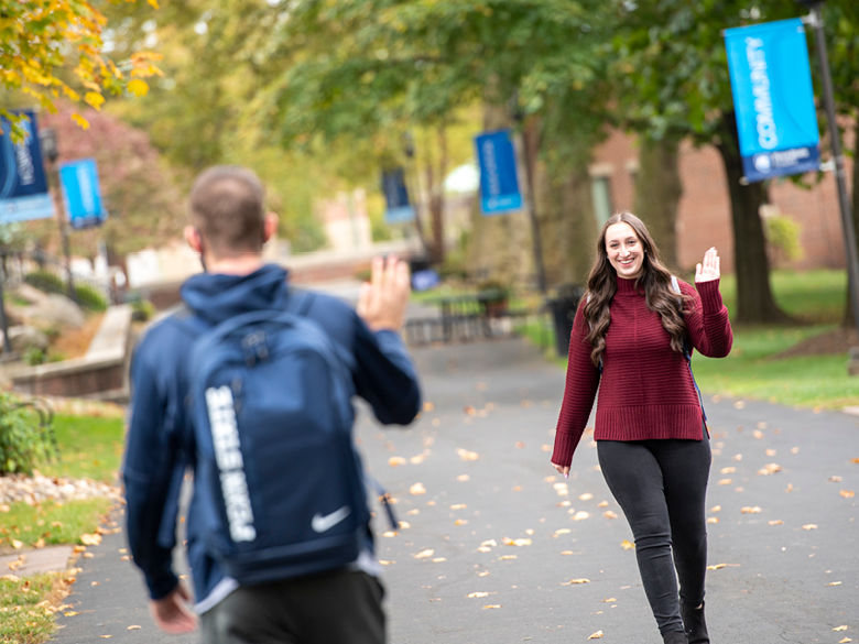 Two students on Penn State Schuylkill's mall walk waving at one another