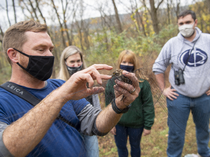 Faculty researcher demonstrates handling of birds to his students.