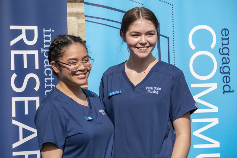 Student nurses wear navy scrubs and pose for photo.