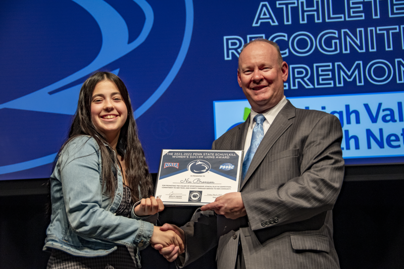 Photo of female student-athlete shaking a man's hand as she is presented with an award