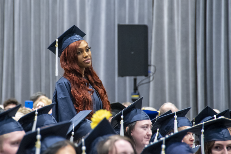 A student stands during commencement.