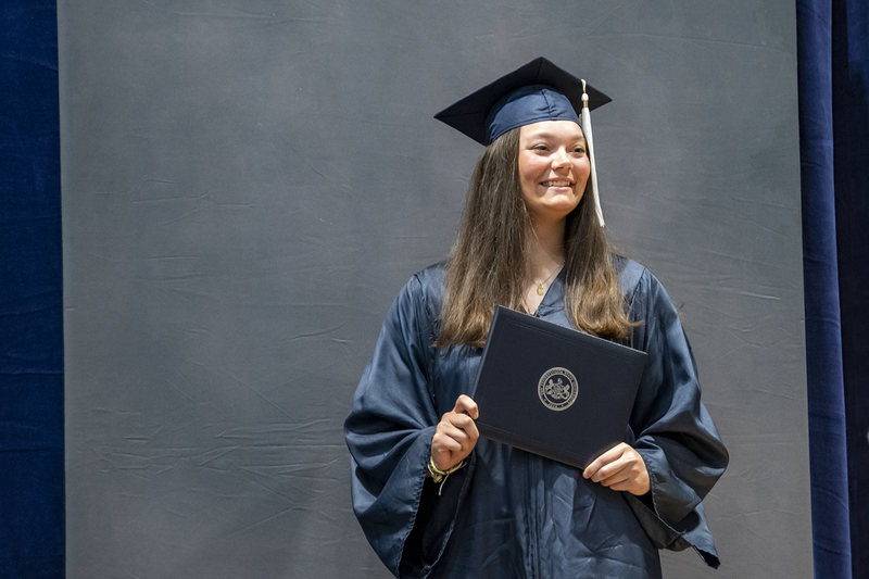 A female graduate poses with diploma.