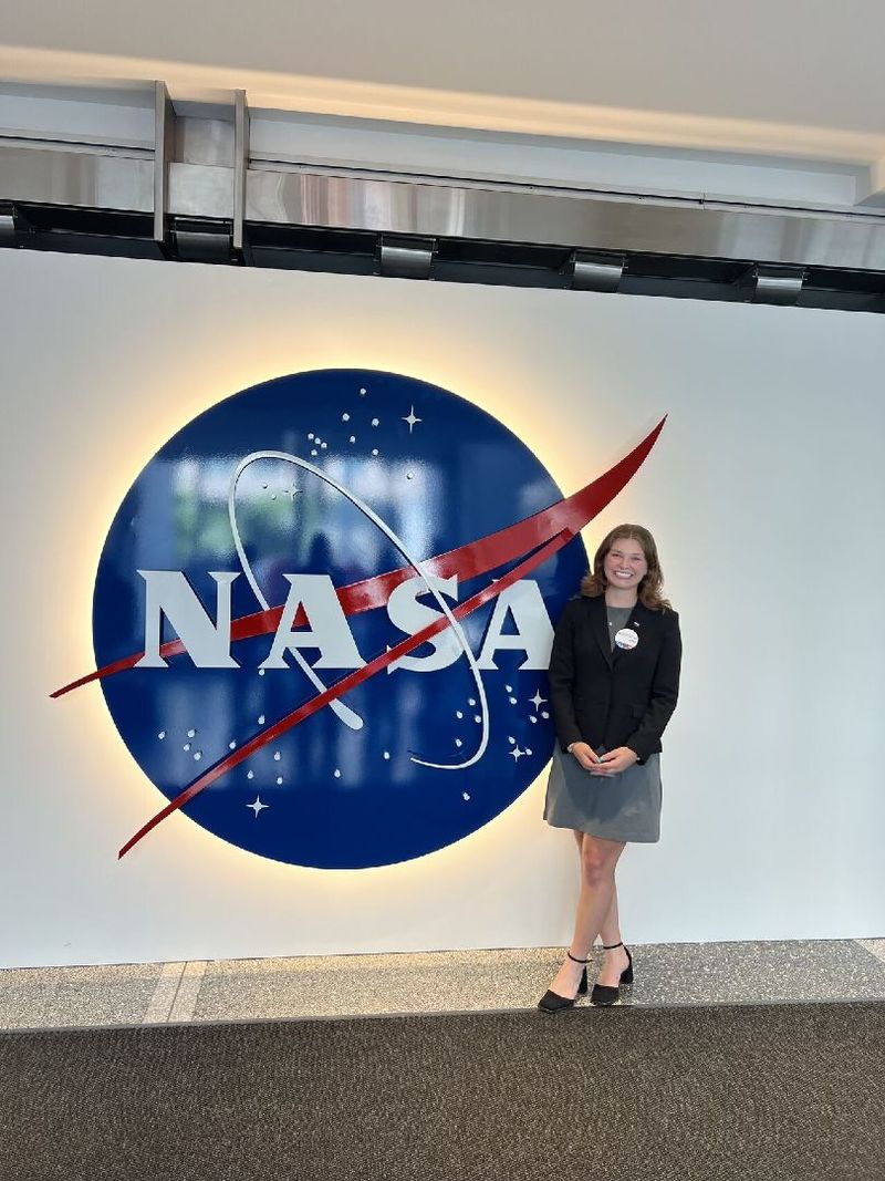 A student stands next to a NASA sign