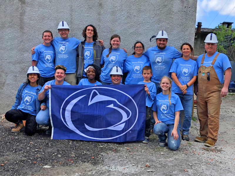 A group of Penn Staters proudly pose in front of their Portugal-based Habitat for Humanity build site.