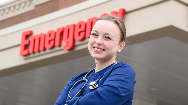 Caucasian female standing in scrubs outside of a hospital