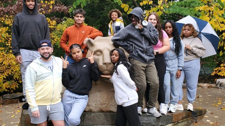 group of students standing in front of lion statue