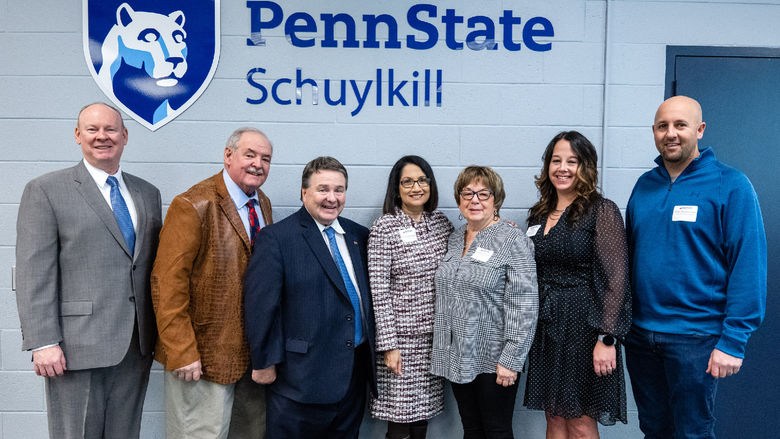 Attendees from the Schuylkill Chamber Business Executive Forum pose in front of a Penn State logo