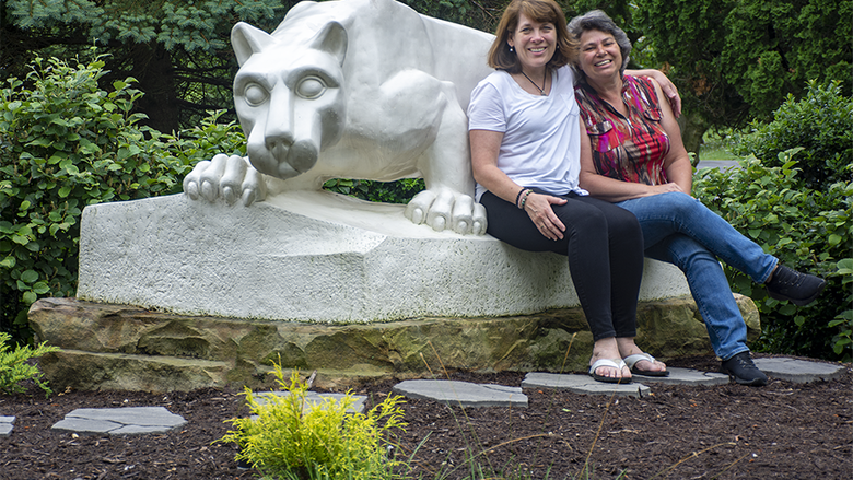 Jeanne Elberfeld, left, sits atop Penn State Schuylkill's lion shrine with her arm draped around Andrea Solinski, right
