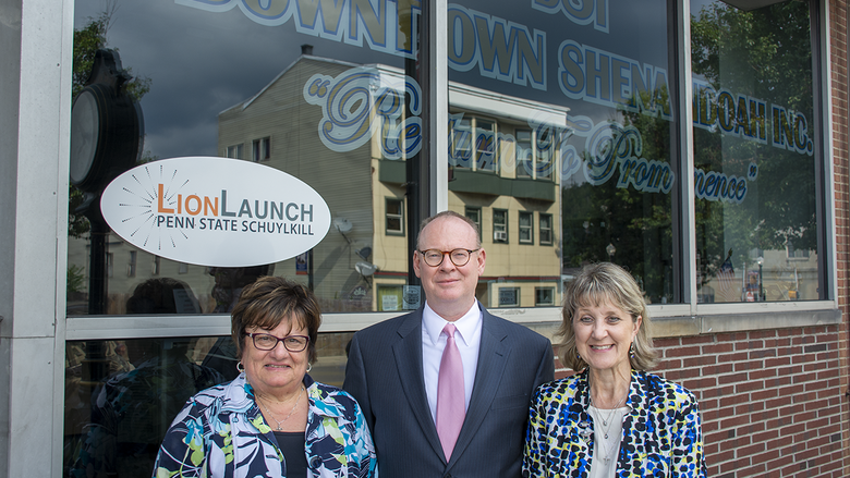Three people stand in front of a glass storefront with a "LionLaunch Penn State Schuylkill" logo on the glass behind them.