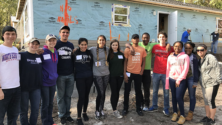 A group of Schuylkill campus student volunteers take a break to pose for a photo in front of their Habitat for Humanity job site.