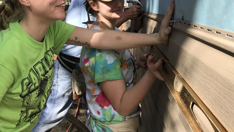 Students install vinyl siding during a Habitat for Humanity build in Florida.