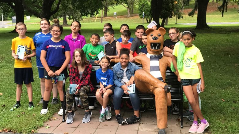 STEM Saturday students perch themselves on Penn State Schuylkill's lion bench
