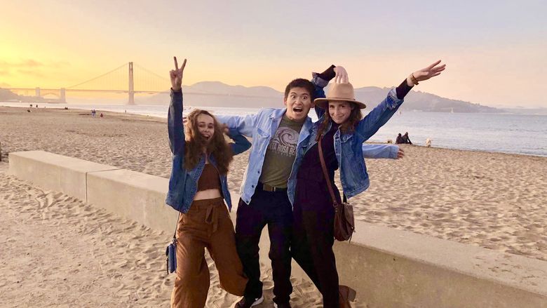 Three students make fun poses while standing on the beach in front of the Golden Gate Bridge in San Francisco, CA