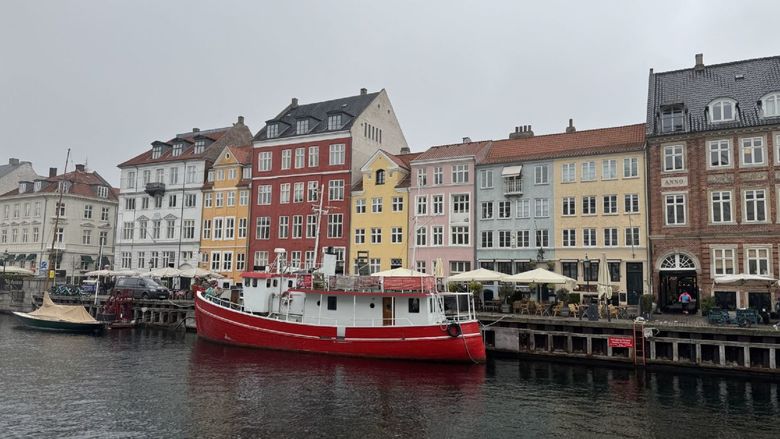 a view of copenhagen, denmark, from a canal with a boat in front of the pier.