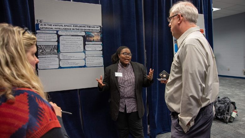 Three people talk in front of a research poster