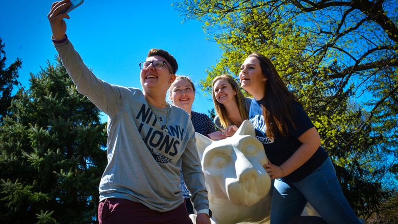 girls take selfie around campus lion shrine