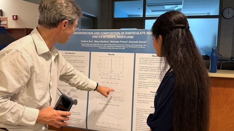 A professor comments on a student's research poster