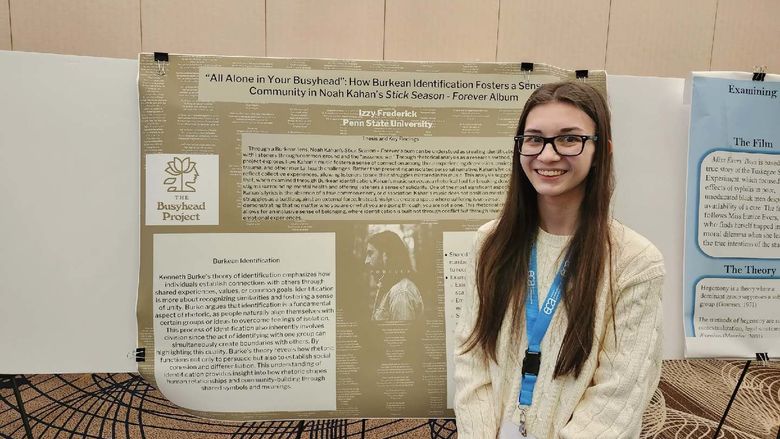 Izzy next to her poster