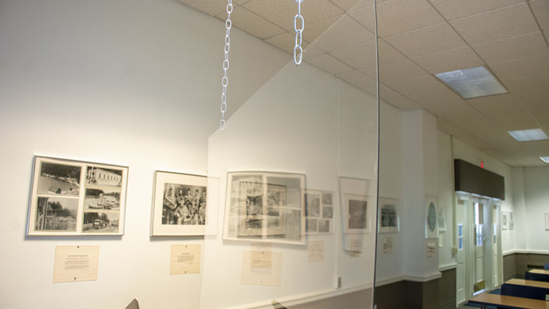 A sheet of plexiglass hangs by chains from a ceiling.