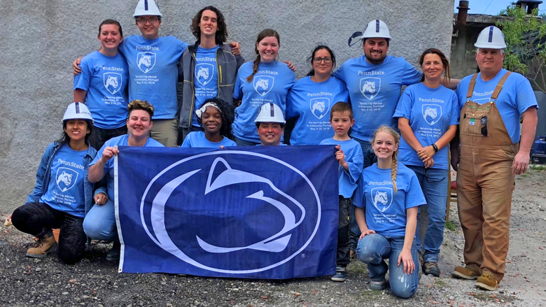 A group of Penn Staters proudly pose in front of their Portugal-based Habitat for Humanity build site.
