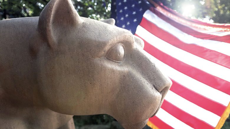 The flag shines behind the Nittany Lion Shrine