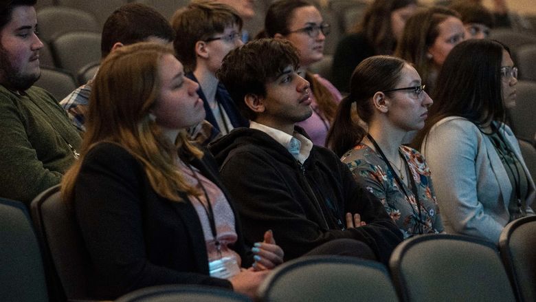 Students sitting in auditorium, listening to presentations