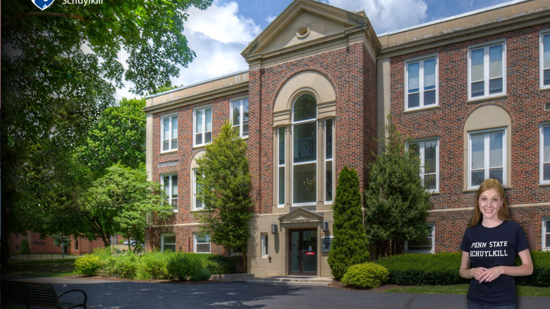 Student tour guide stands outside of the Administration Building.
