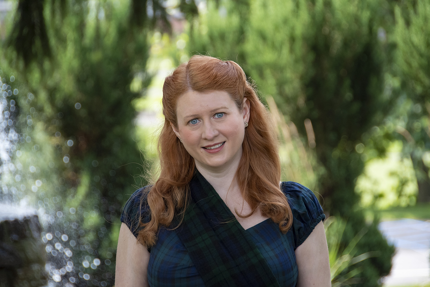 An image of author and professor, Valerie Schrader, against a softly focused campus background.