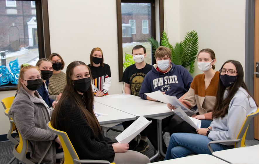 A group of tutors gathers around a work table in the Learning Center.