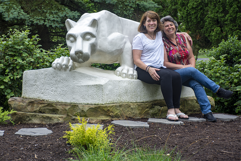 Jeanne Elberfeld, left, sits atop Penn State Schuylkill's lion shrine with her arm draped around Andrea Solinski, right