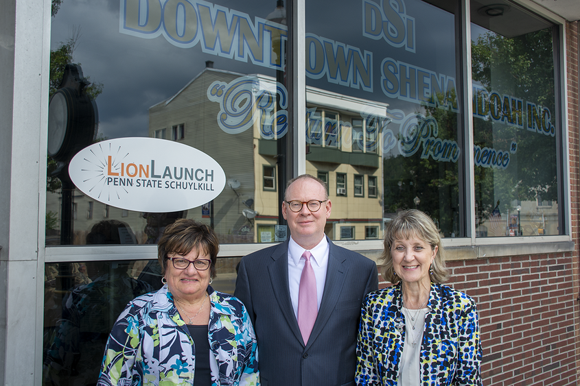 Three people stand in front of a glass storefront with a "LionLaunch Penn State Schuylkill" logo on the glass behind them.