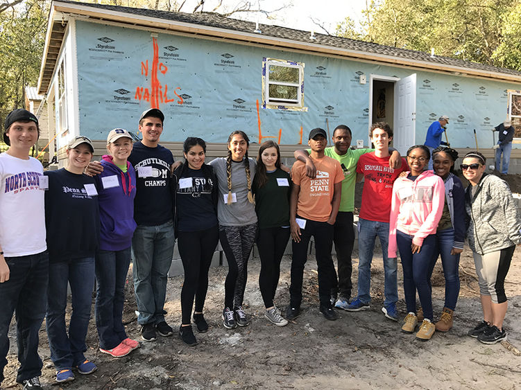 A group of Schuylkill campus student volunteers take a break to pose for a photo in front of their Habitat for Humanity job site.