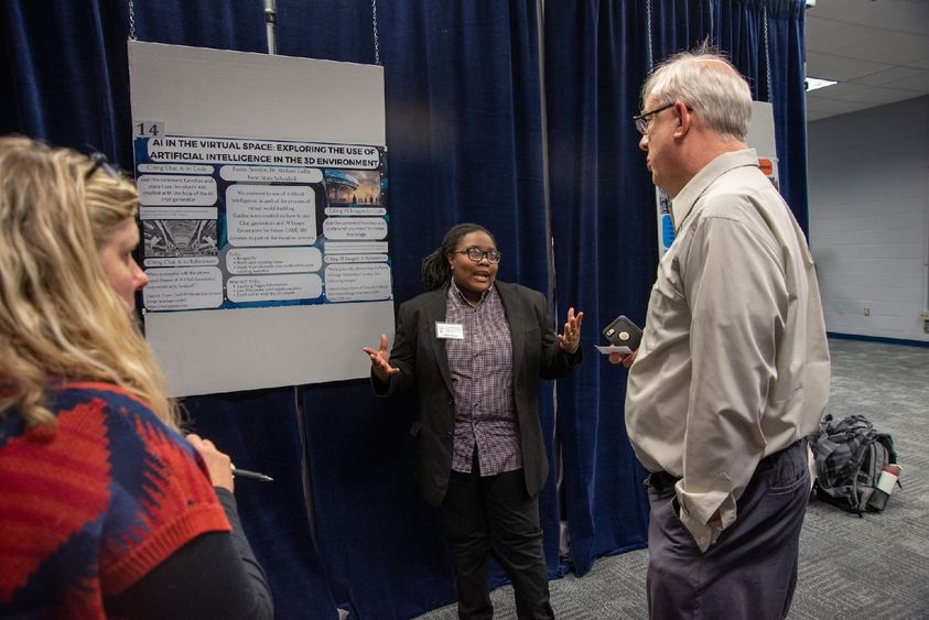 Three people talk in front of a research poster