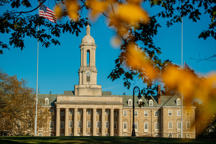 Stone campus building with fall foliage in foreground