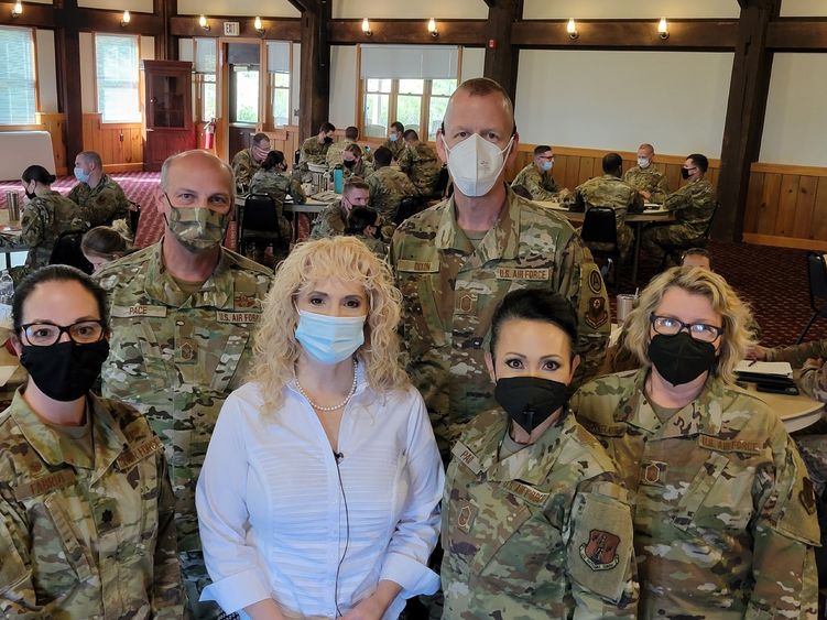 Woman with blond, curly hair stands among members of the Pennsylvania Air National Guard wearing fatigues