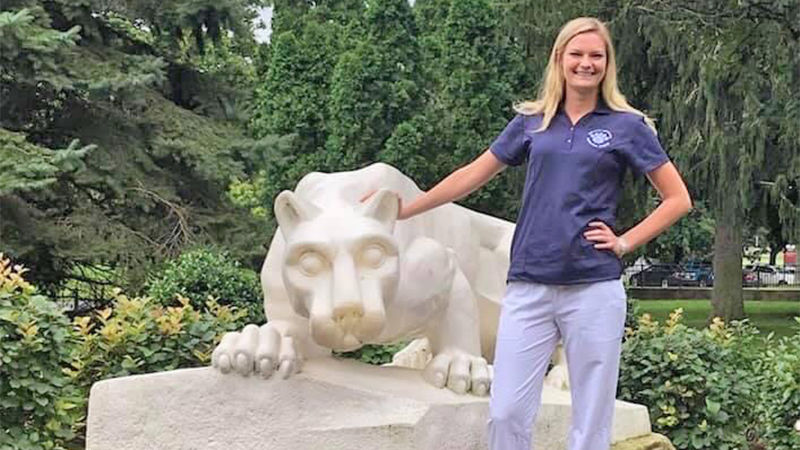 Student in blue scrubs at Penn State Schuylkill's lion shrine.