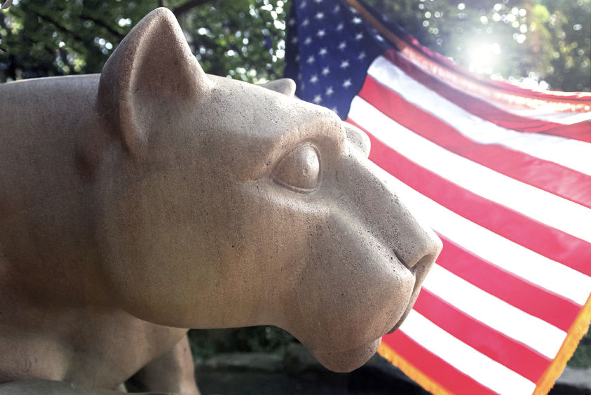 The flag shines behind the Nittany Lion Shrine